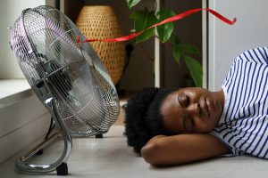 mulher deitada perto de ventilador de chão